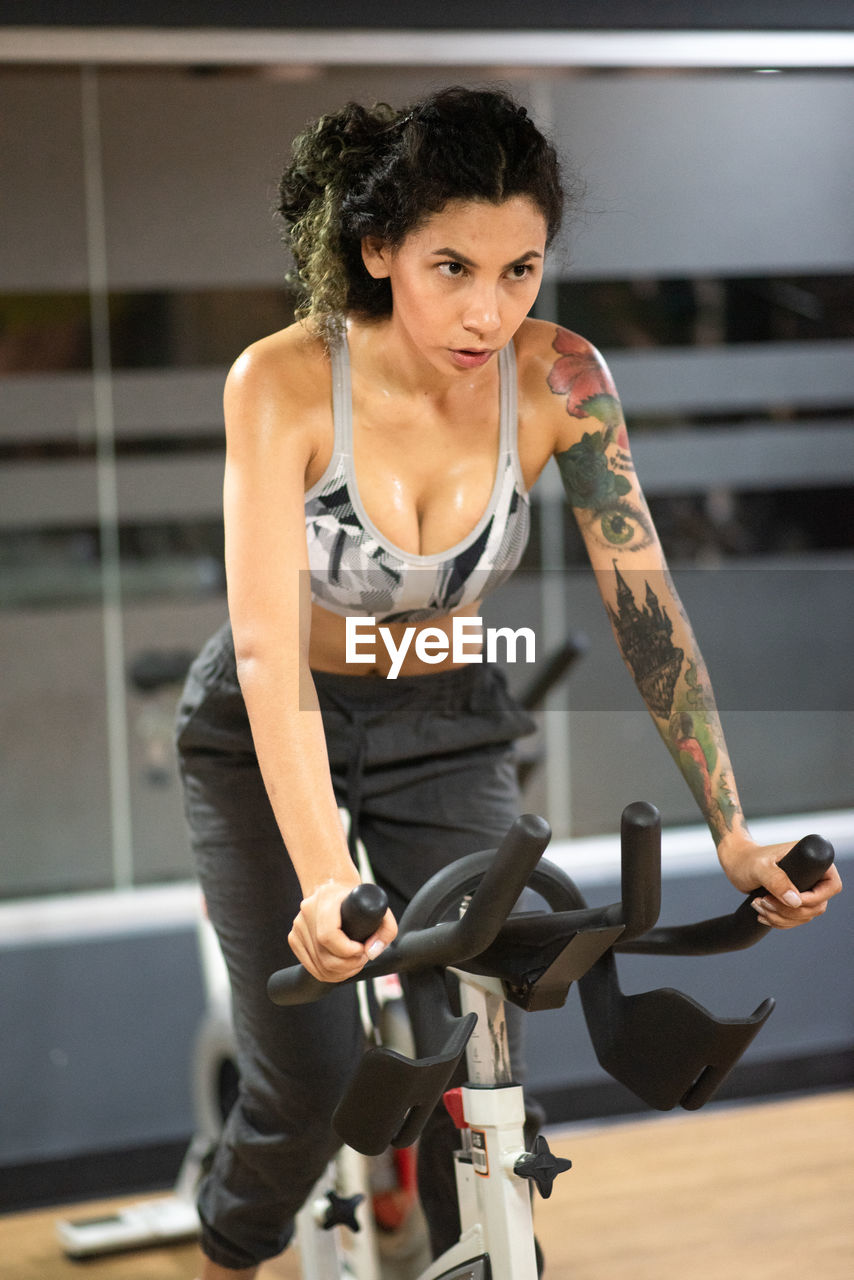 Young woman on bicycle at the gym