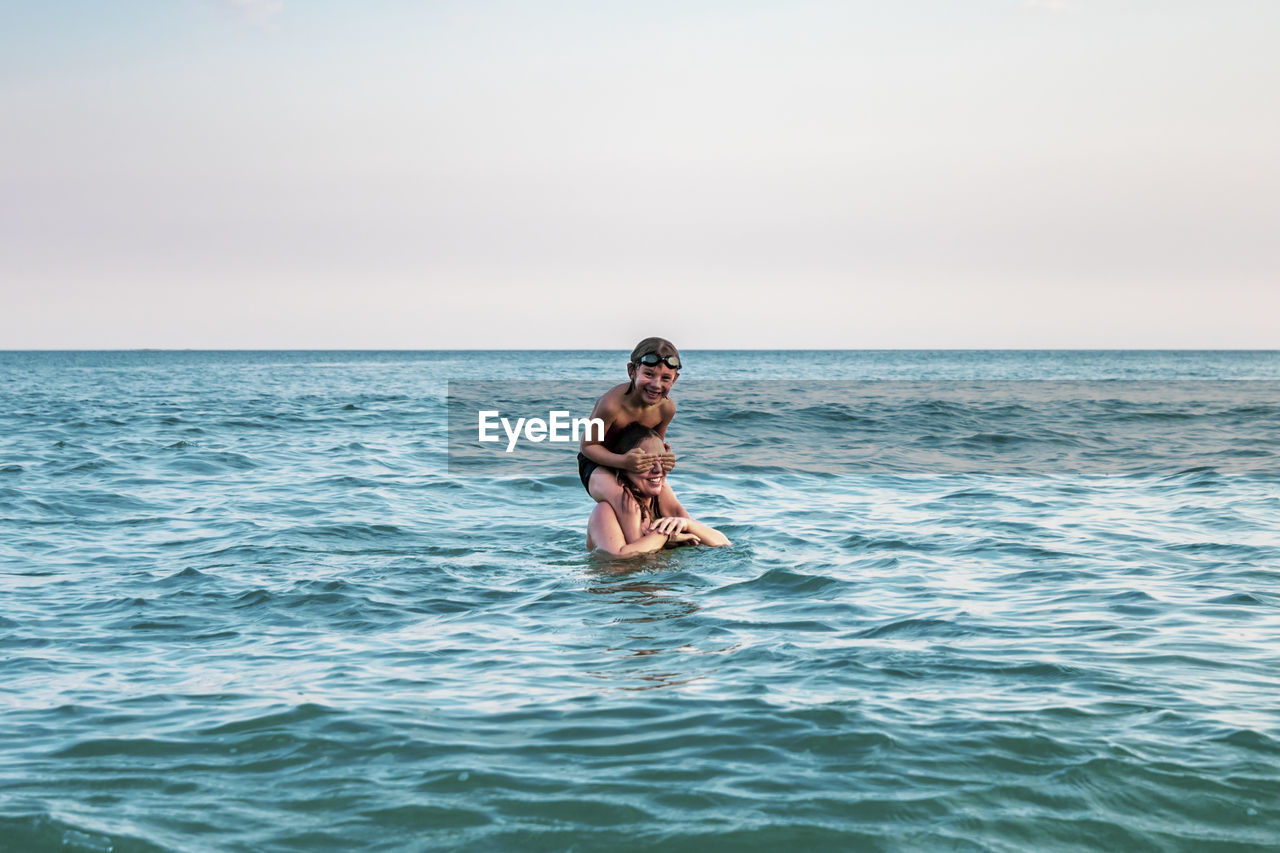 5 years old kid on top of his mother's shoulders, into the ocean