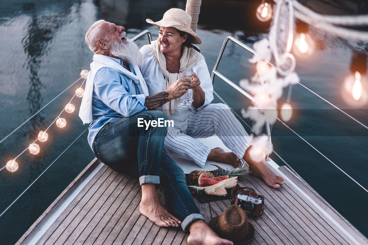 High angle view of cheerful couple sitting on boat at sunset
