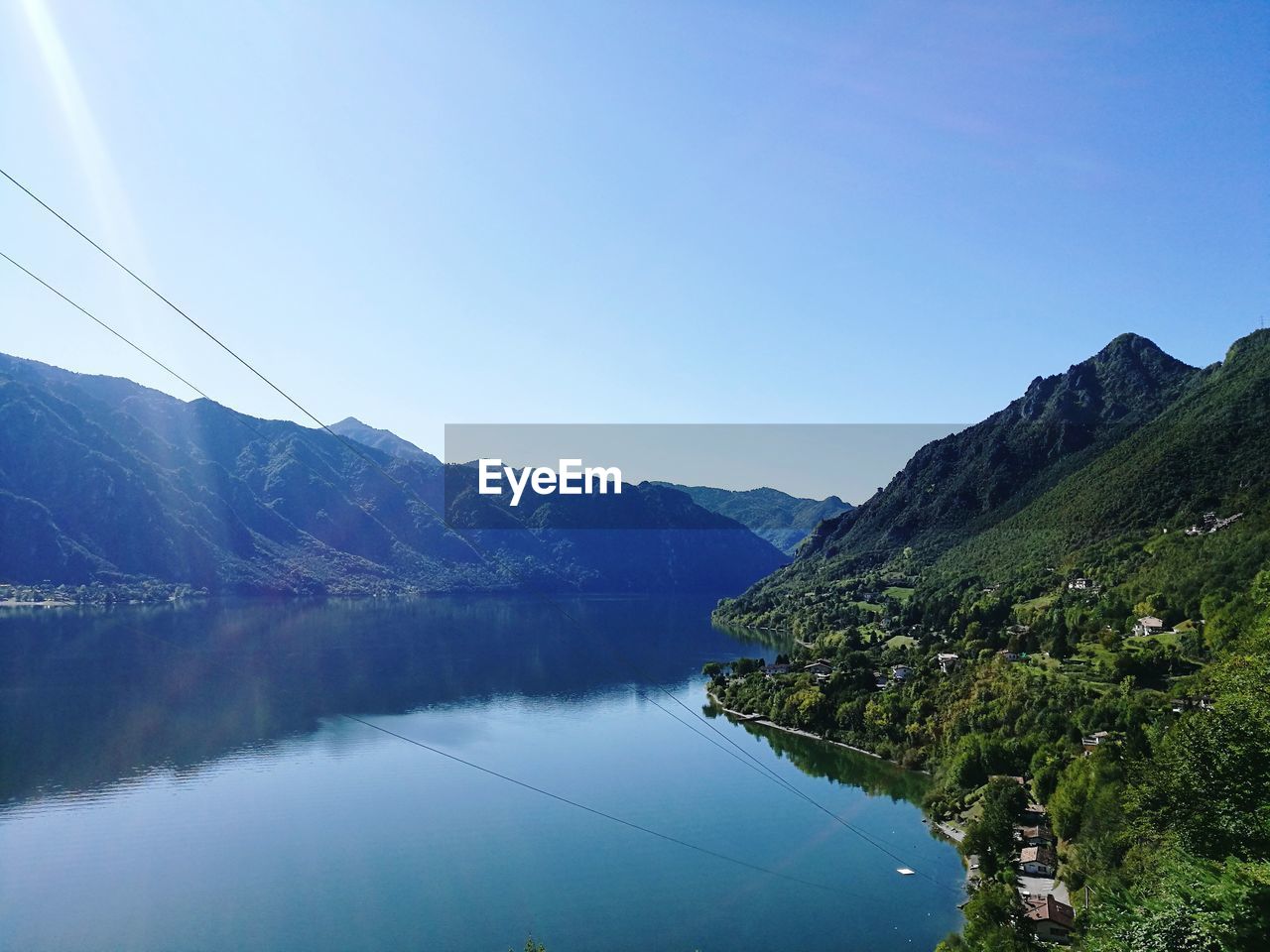 Scenic view of lake and mountains against clear blue sky