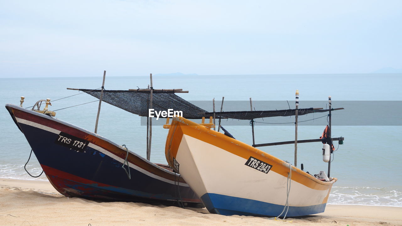 Ship moored on beach against sky