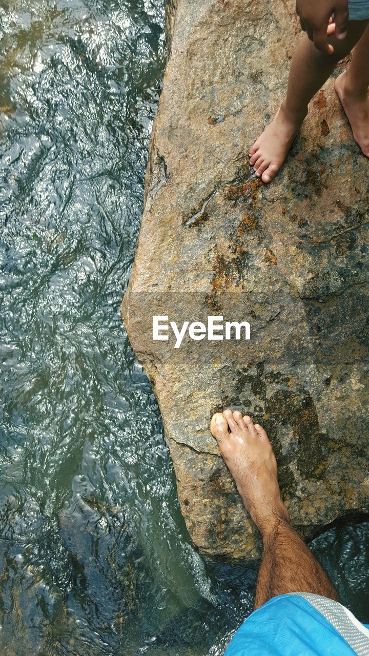 Low section of man standing on rock in river