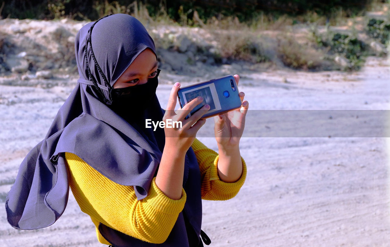 Woman  photographing with mobile phone wearing hijab