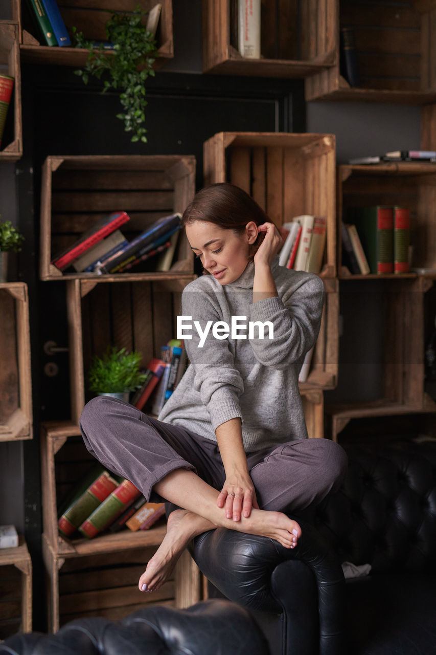 Woman sitting against shelf