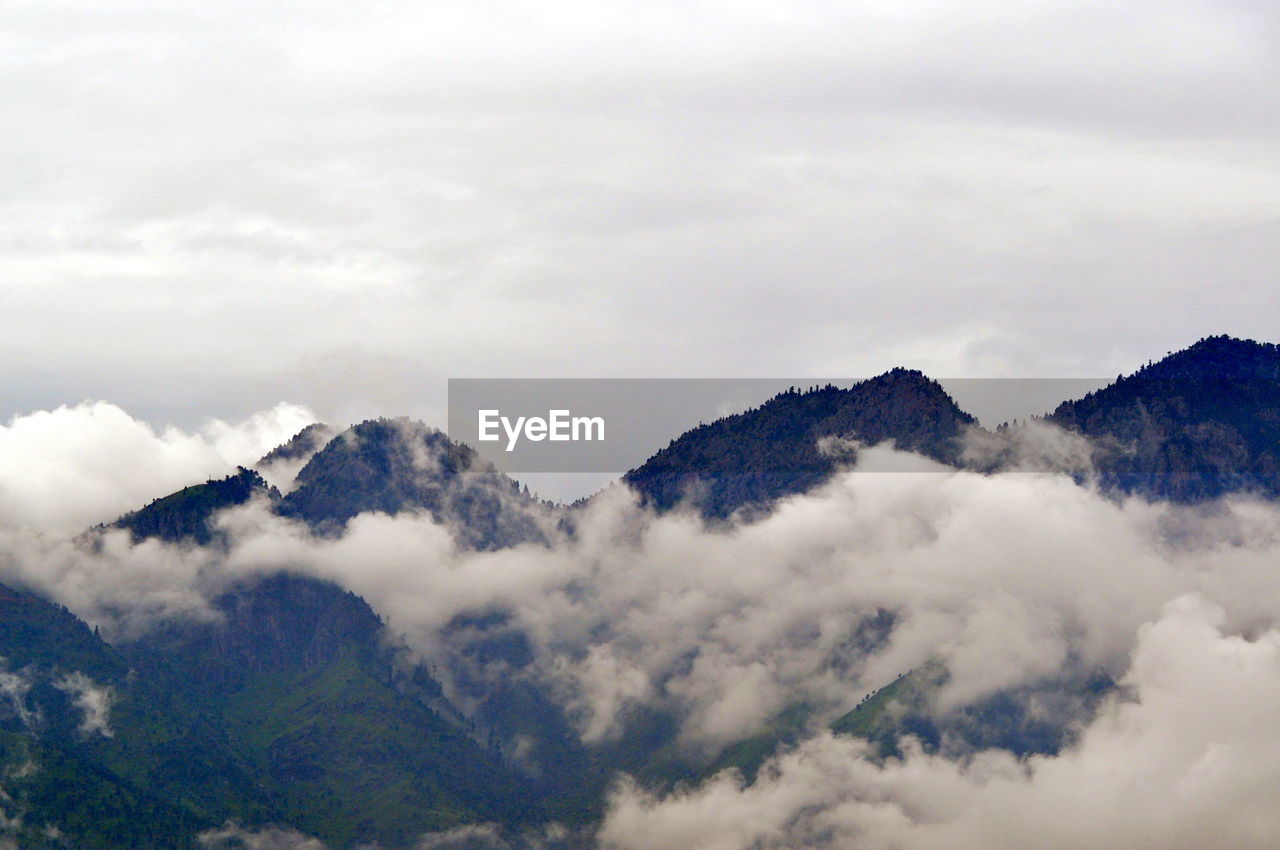 LOW ANGLE VIEW OF CLOUDS OVER MOUNTAINS AGAINST SKY