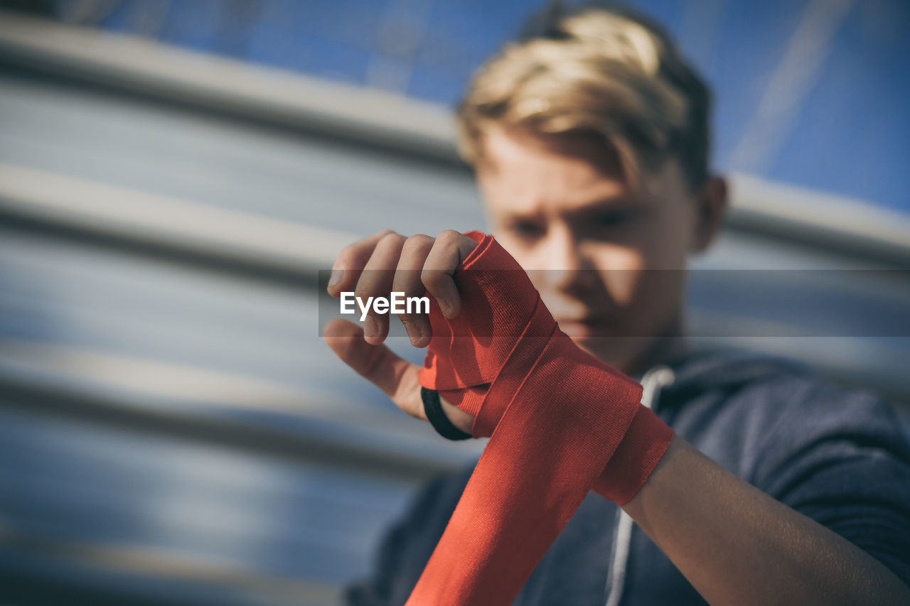 Low angle view of boy wearing red strap while standing outdoors