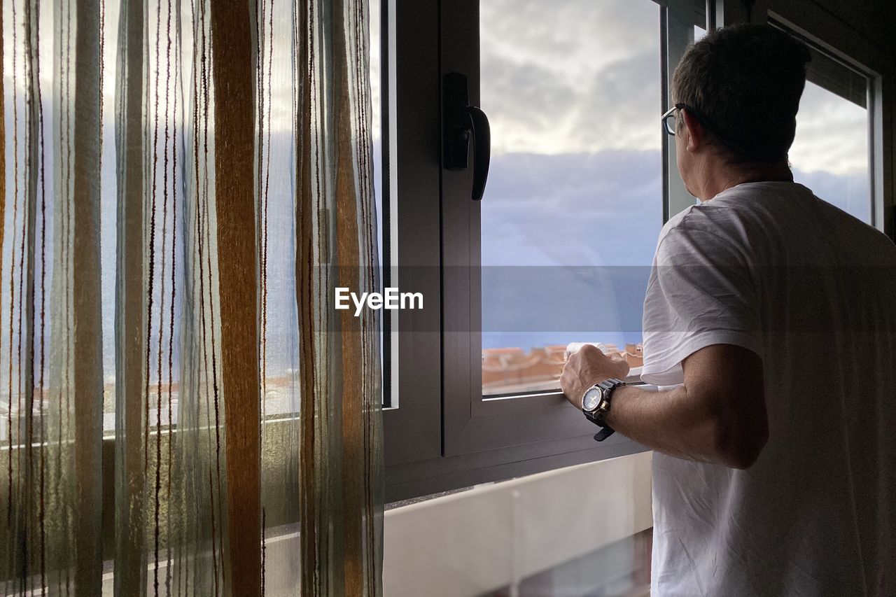 Rear view of man looking through window