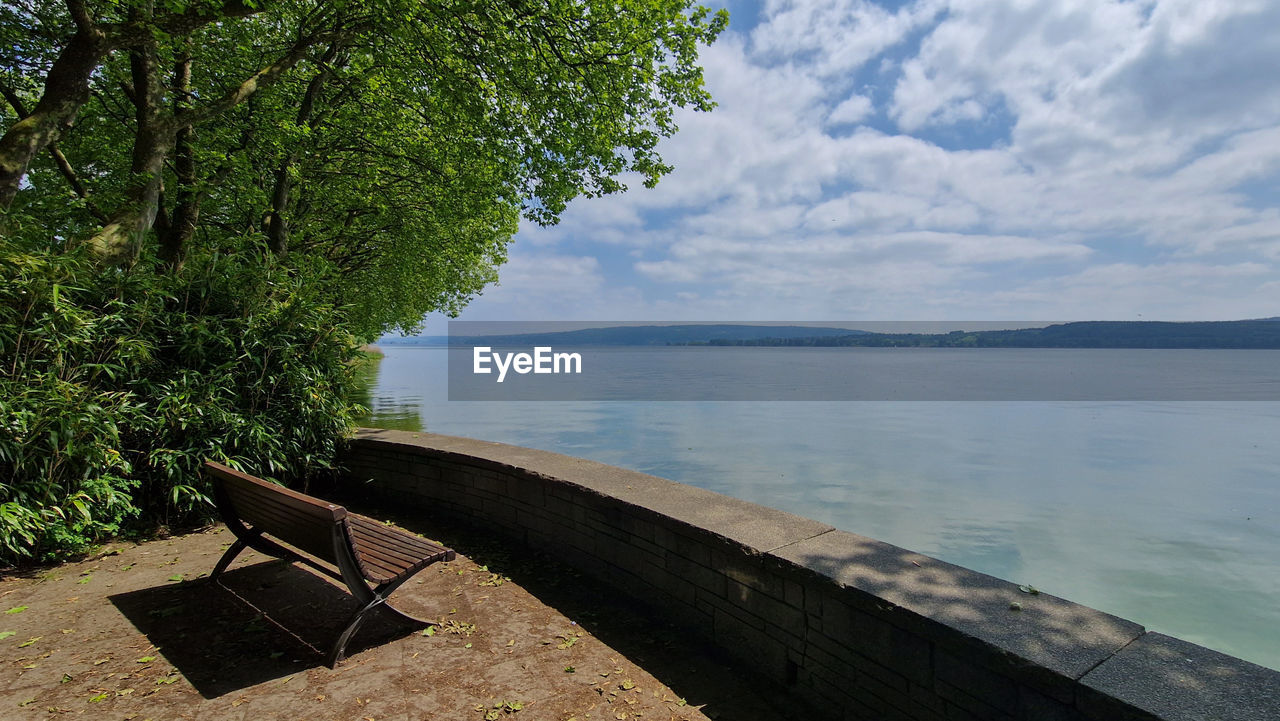 water, nature, tranquility, tree, plant, beauty in nature, scenics - nature, sky, tranquil scene, sea, cloud, no people, shore, day, land, beach, outdoors, seat, travel destinations, idyllic, wood, body of water, travel, non-urban scene, environment, relaxation, sunlight, bay, landscape, coast, reservoir, tourism, bench, vacation, trip, architecture, holiday, mountain