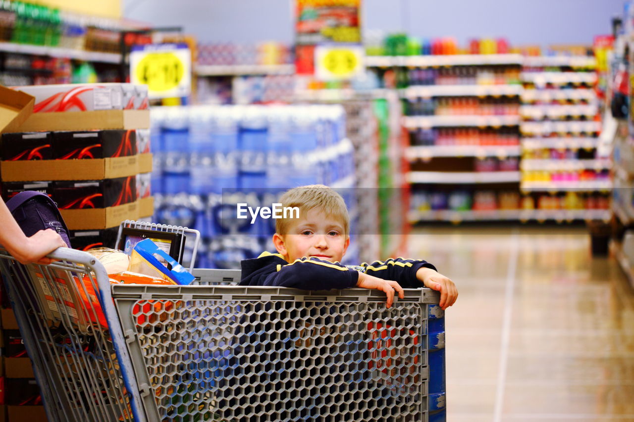 Portrait of boy sitting in shopping cart at store