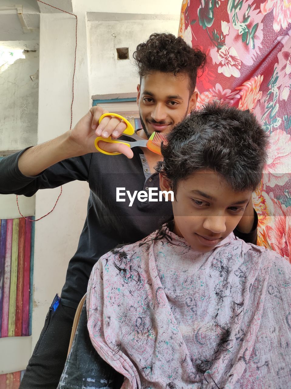 Low angle portrait of man cutting boy hair in salon
