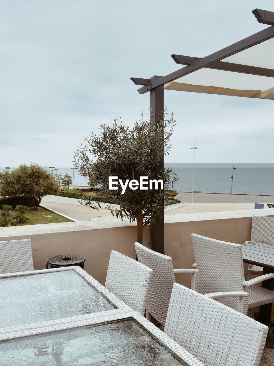 EMPTY CHAIR BY SWIMMING POOL AGAINST SEA