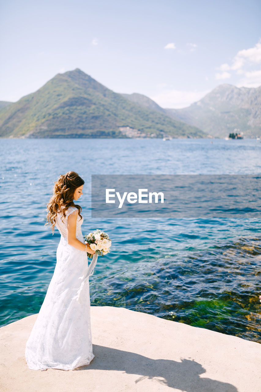 Full length of bride standing against lake
