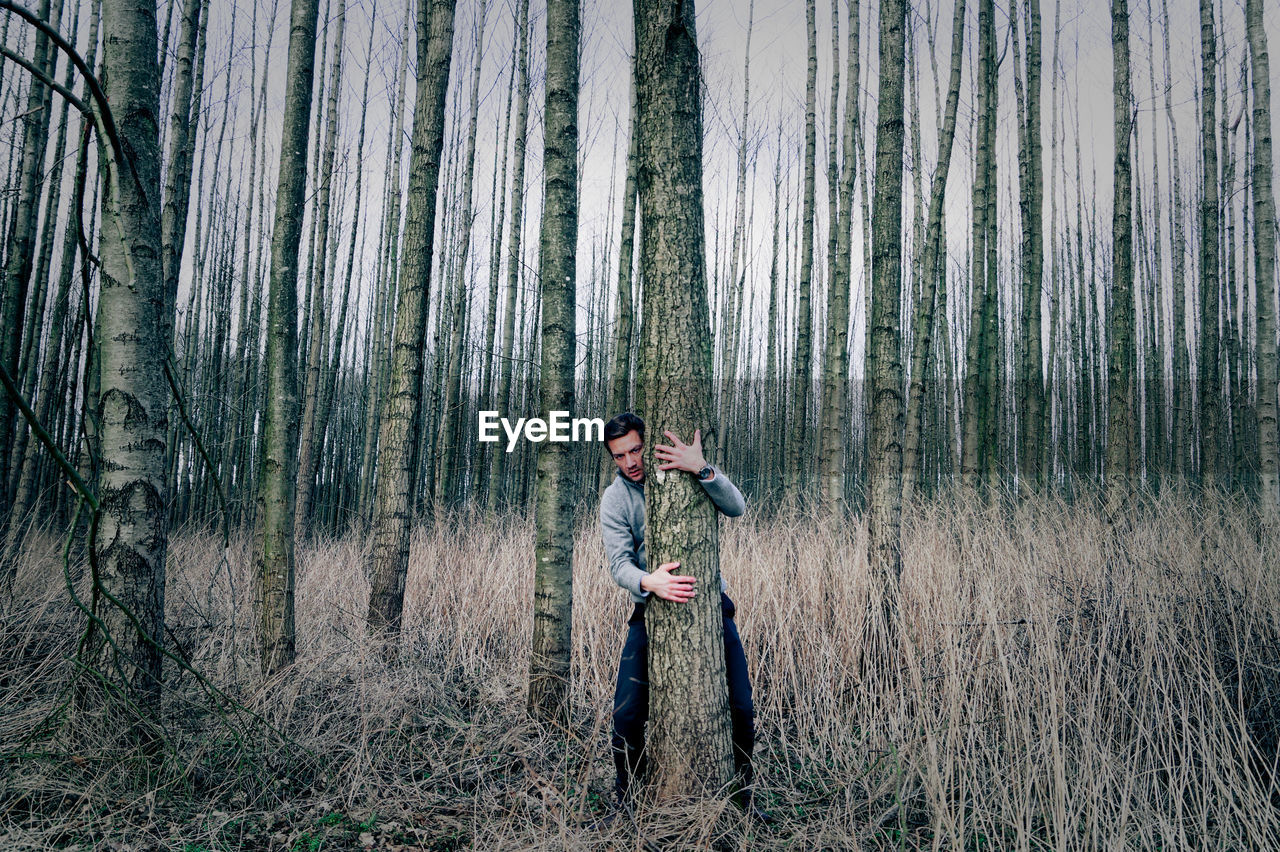 Man hugging tree in forest