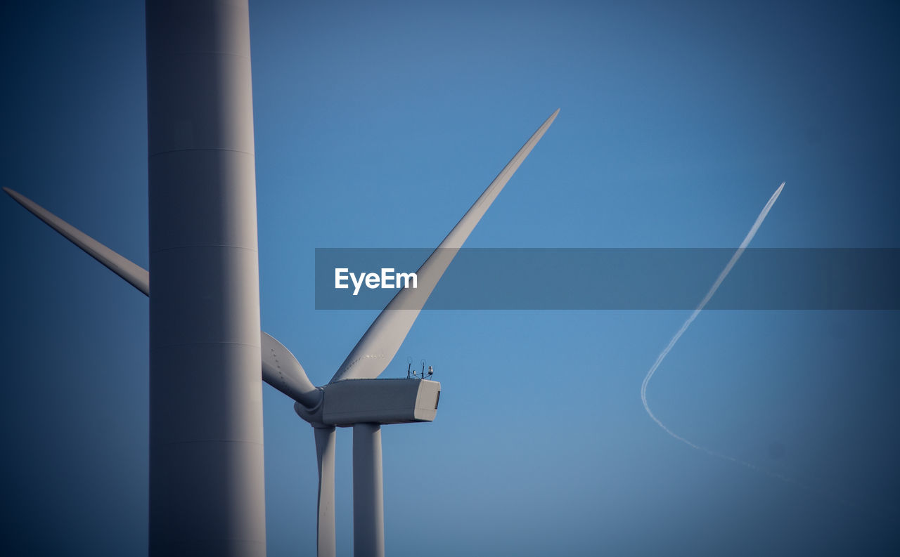 Low angle view of wind turbine against blue sky