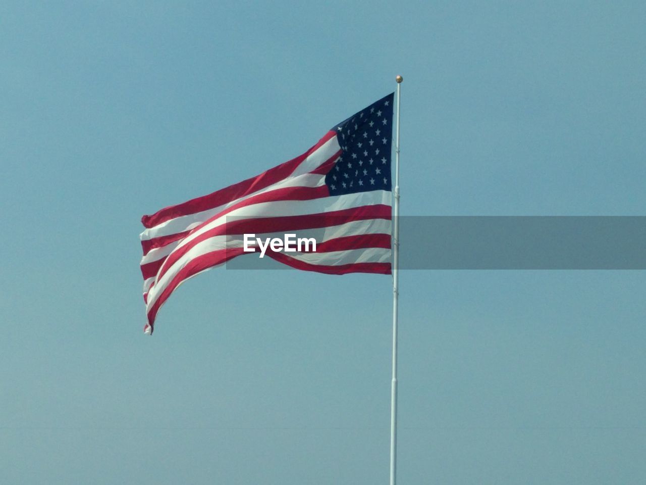 Low angle view of american flag against clear blue sky