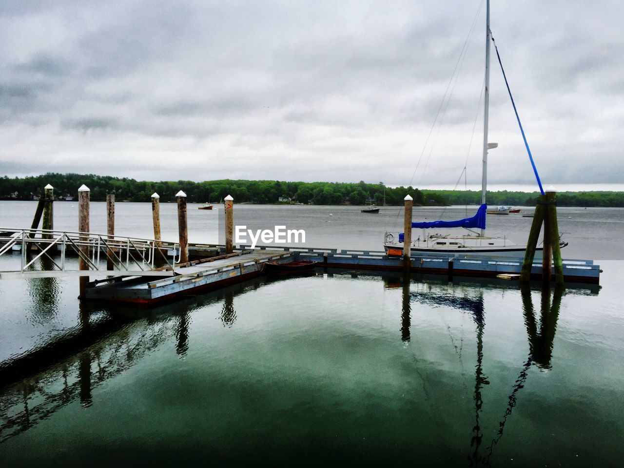 Boat moored at harbor against cloudy sky