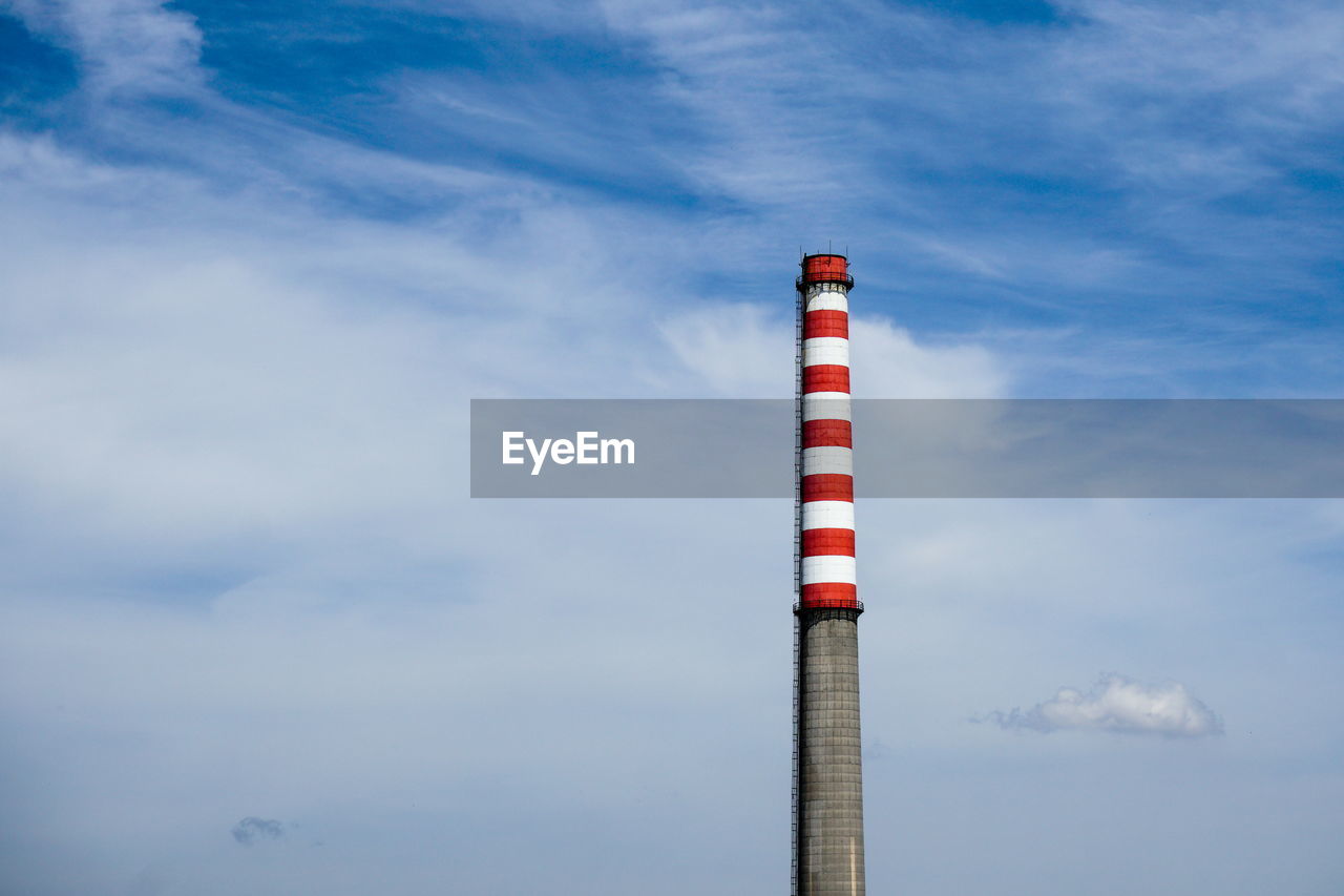 Low angle view of smoke stack against cloudy sky