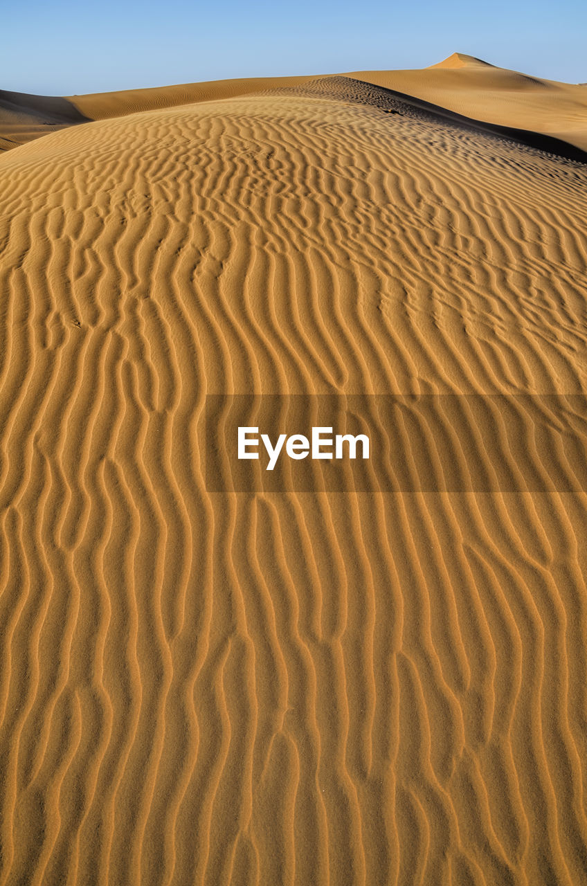 Sand dunes in desert against clear sky