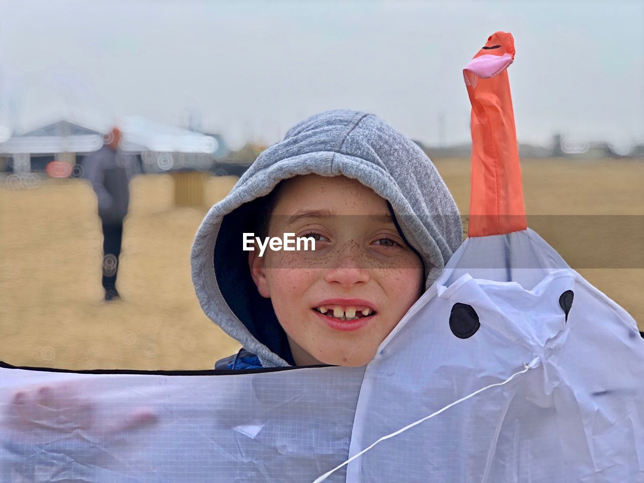 Close-up portrait of boy holding kite while standing on field