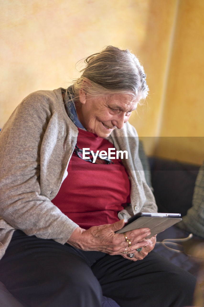 Smiling senior woman using digital tablet at home