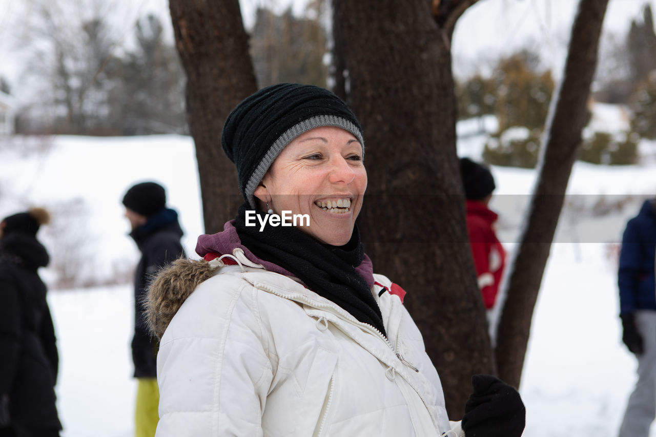 Smiling woman standing by tree outdoors