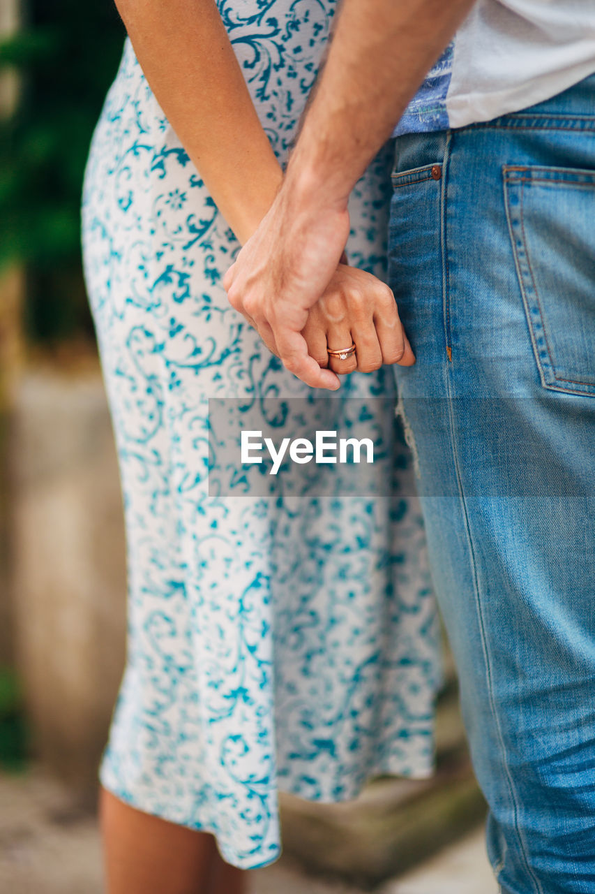 REAR VIEW OF WOMEN STANDING IN FRONT OF HANDS