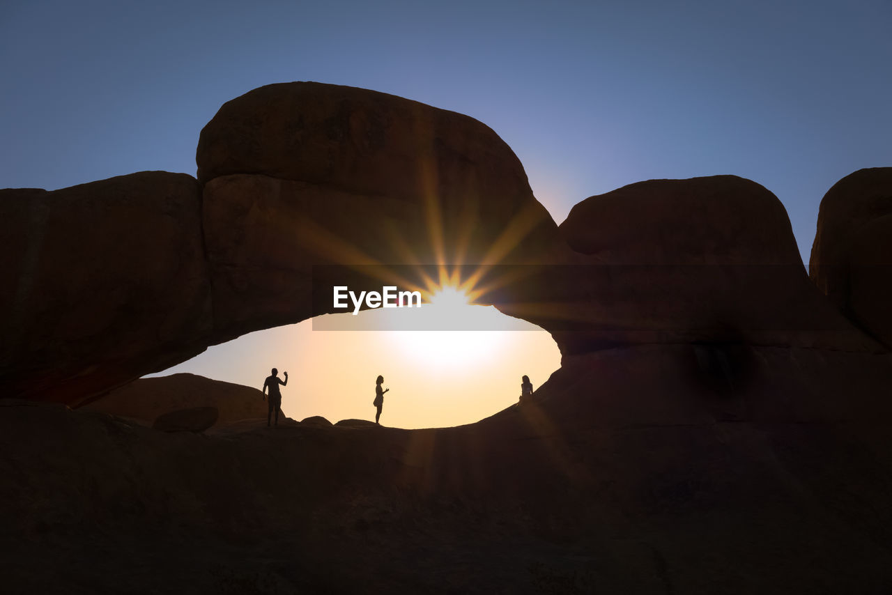 People standing on rock formation at spitzkoppe namibia during sunset