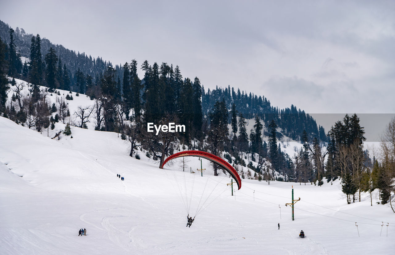 Woman paragliding against snowcapped mountain