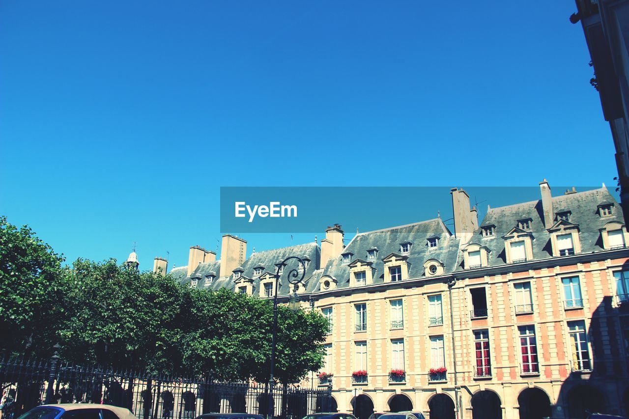 Low angle view of place des vosges against clear blue sky