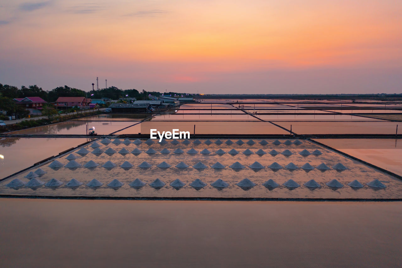 HIGH ANGLE VIEW OF ROOF AND BUILDINGS AGAINST SKY DURING SUNSET