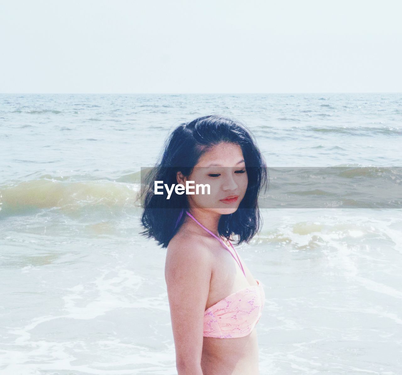 HAPPY WOMAN STANDING ON BEACH AGAINST SEA