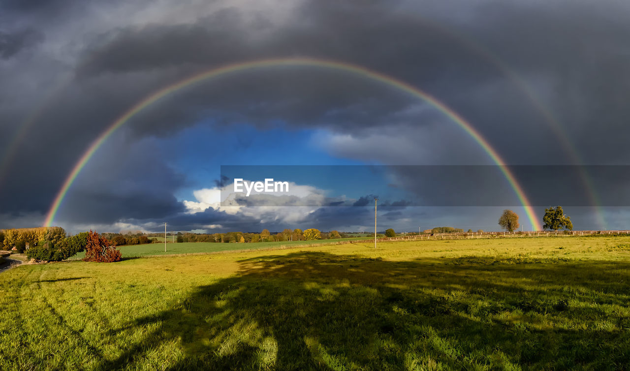 Scenic view of rainbow over field against sky