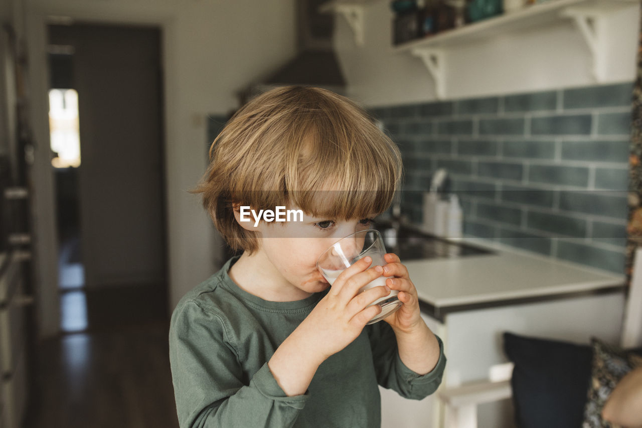 Boy in kitchen drinking milk