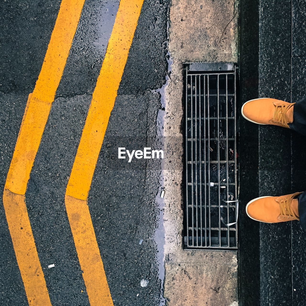 Low section of person wearing yellow shoes standing on footpath