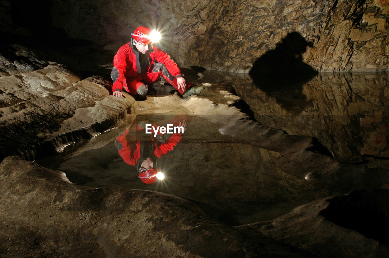 Reflection of a spelunker in a cave water pool. carbide acetylene gas lamp on helmet 