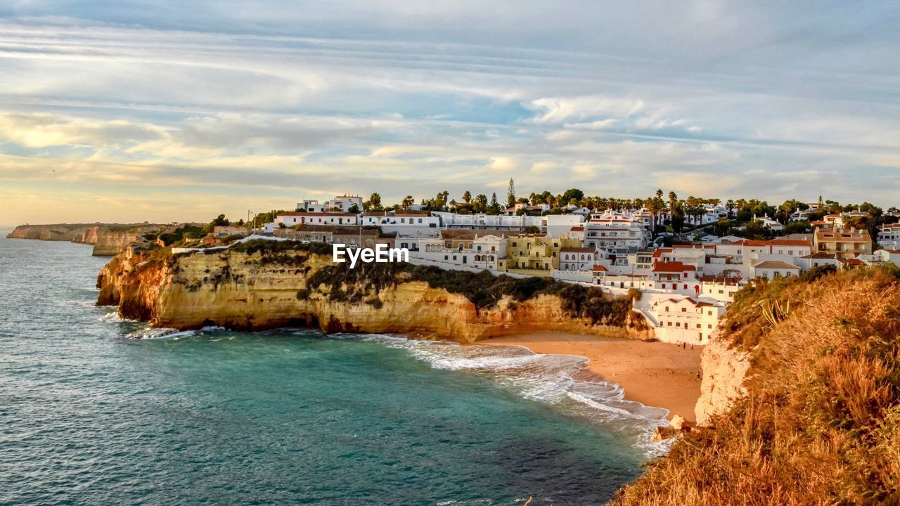 Scenic view of beach by city against sky