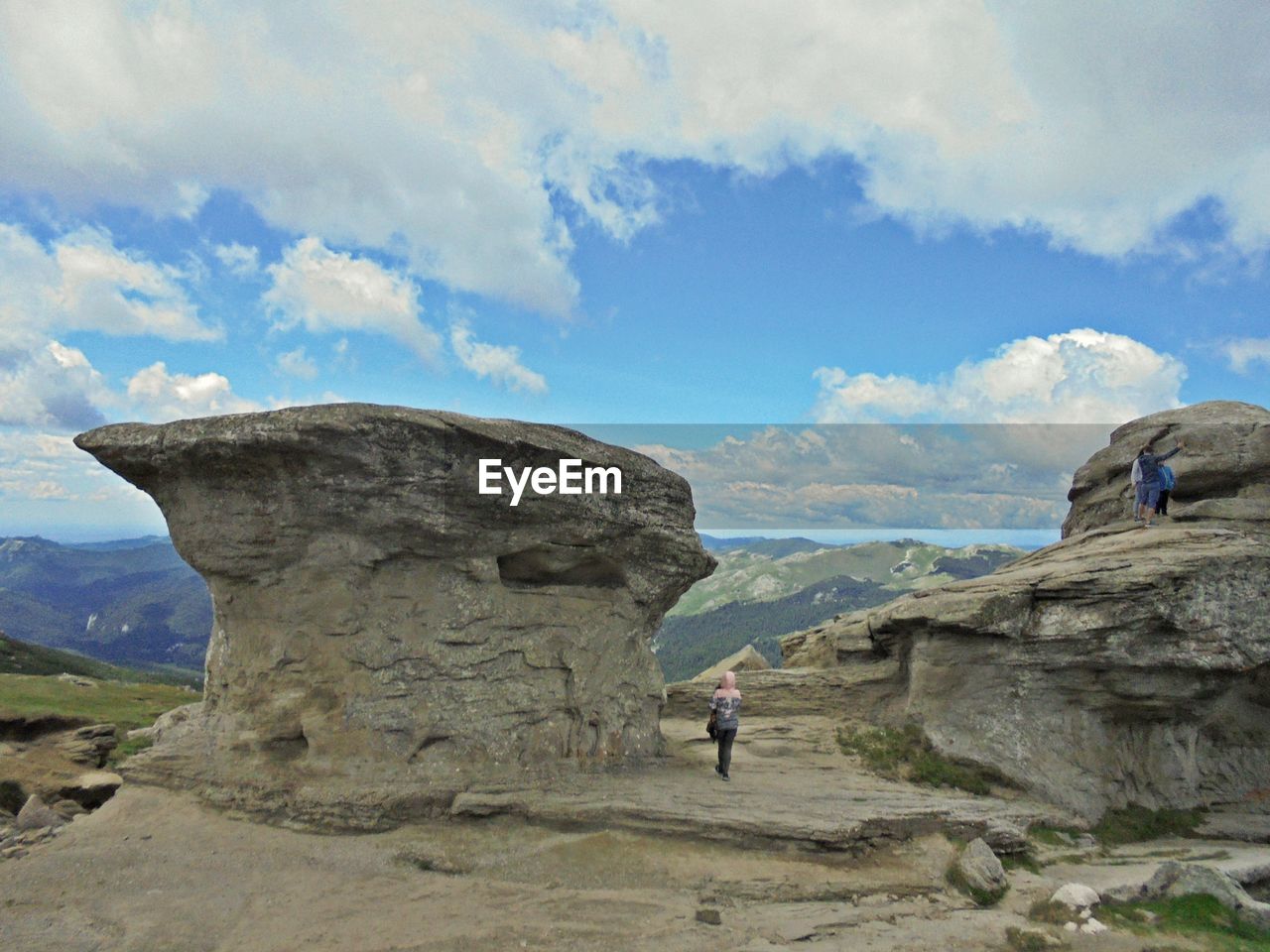 PEOPLE ON ROCK FORMATIONS AGAINST SKY