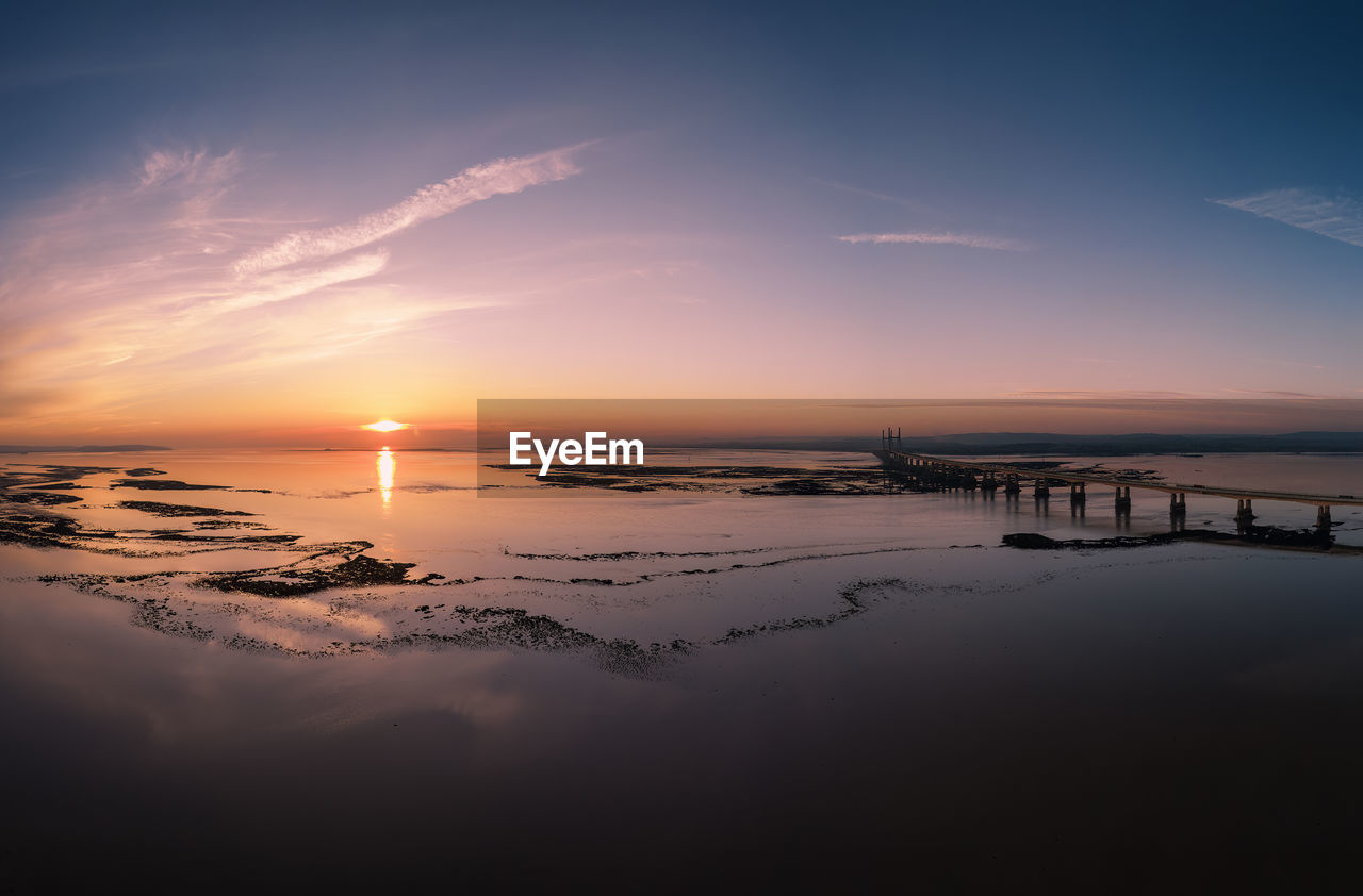 sky, water, sunset, sea, scenics - nature, beauty in nature, nature, reflection, horizon, dawn, cloud, tranquility, environment, tranquil scene, beach, sun, horizon over water, land, no people, landscape, ocean, travel destinations, outdoors, travel, architecture, evening, idyllic, sunlight, dramatic sky, blue, seascape, afterglow, wave, built structure, orange color, tourism, twilight
