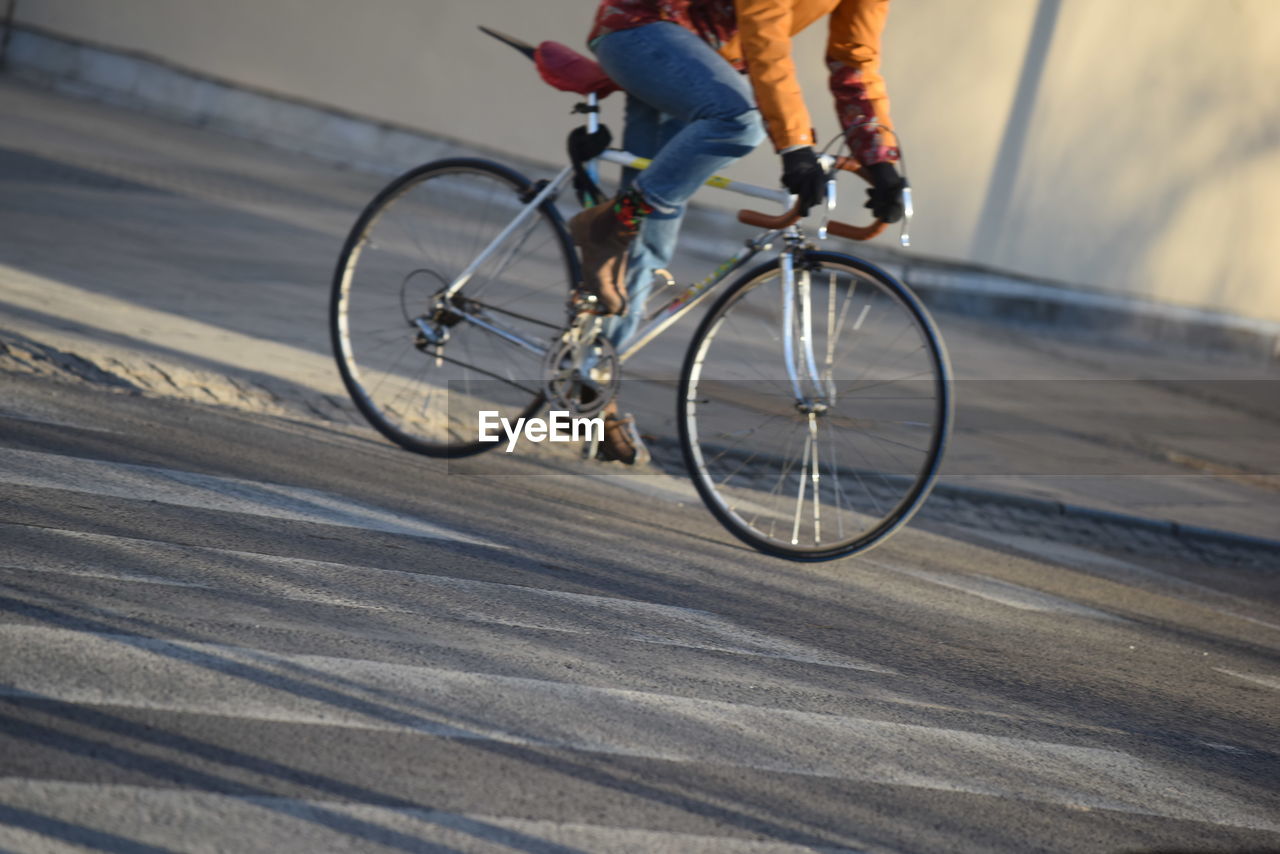 Low section of man riding bicycle on road