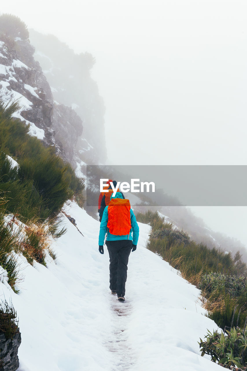 Rear view of people walking on snow covered land