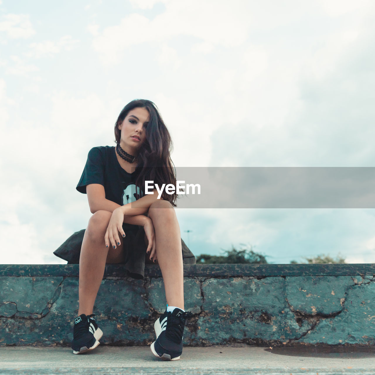 PORTRAIT OF BEAUTIFUL WOMAN SITTING AGAINST SKY