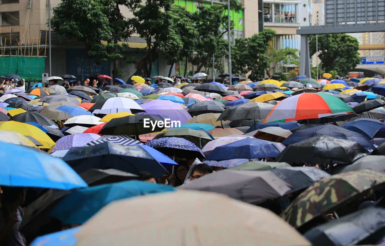 People with multi colored umbrellas in city during rainy season