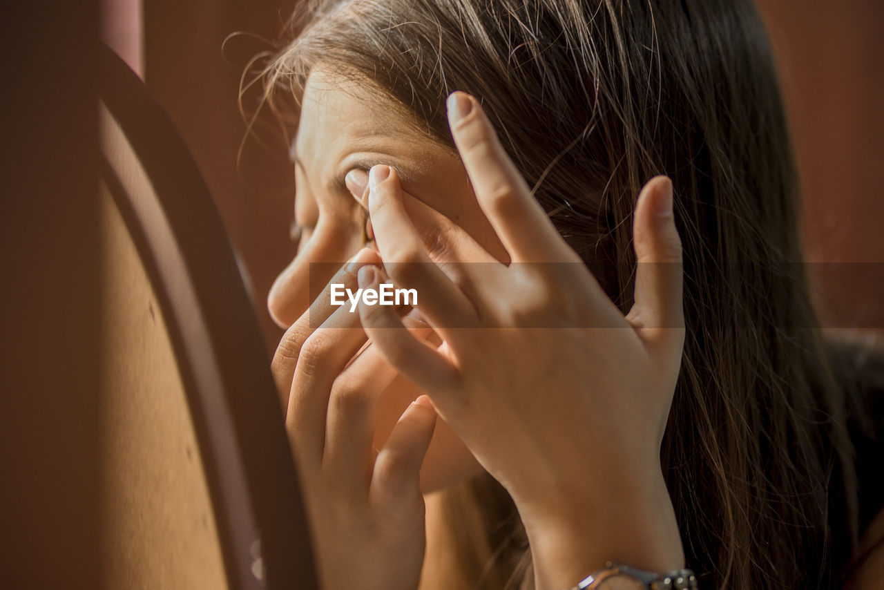 Close-up of young woman applying make-up