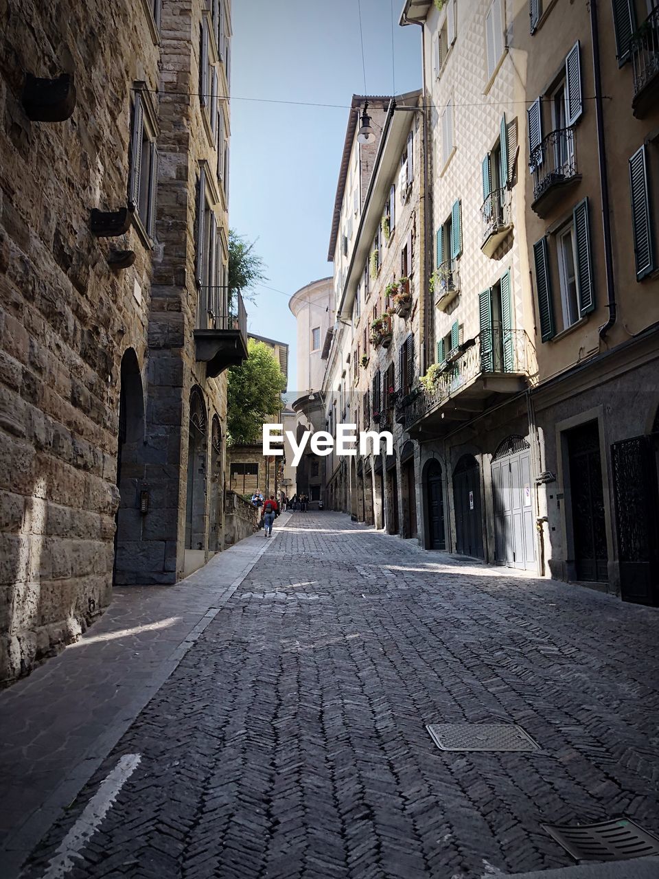 NARROW STREET AMIDST BUILDINGS AGAINST SKY