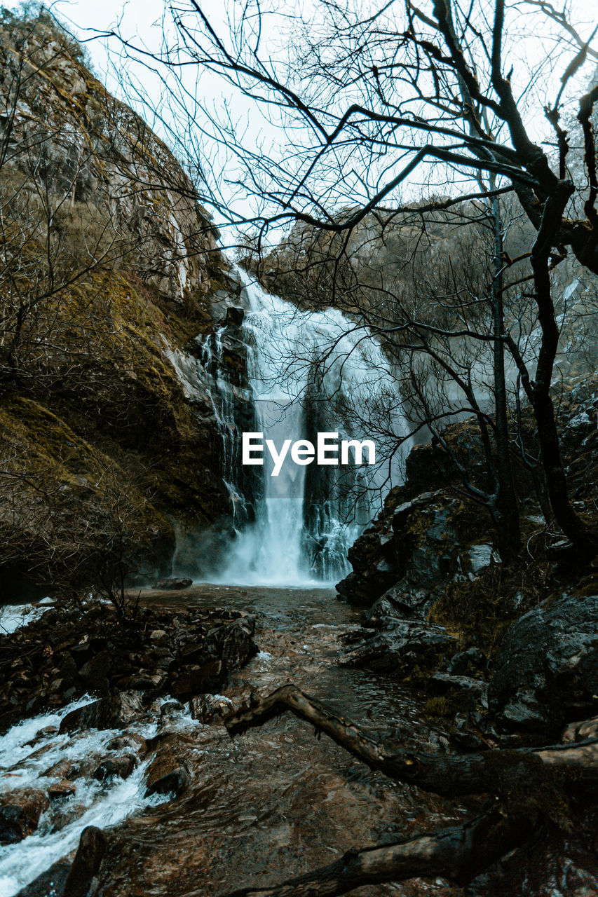 SCENIC VIEW OF WATERFALL AGAINST ROCKS IN FOREST