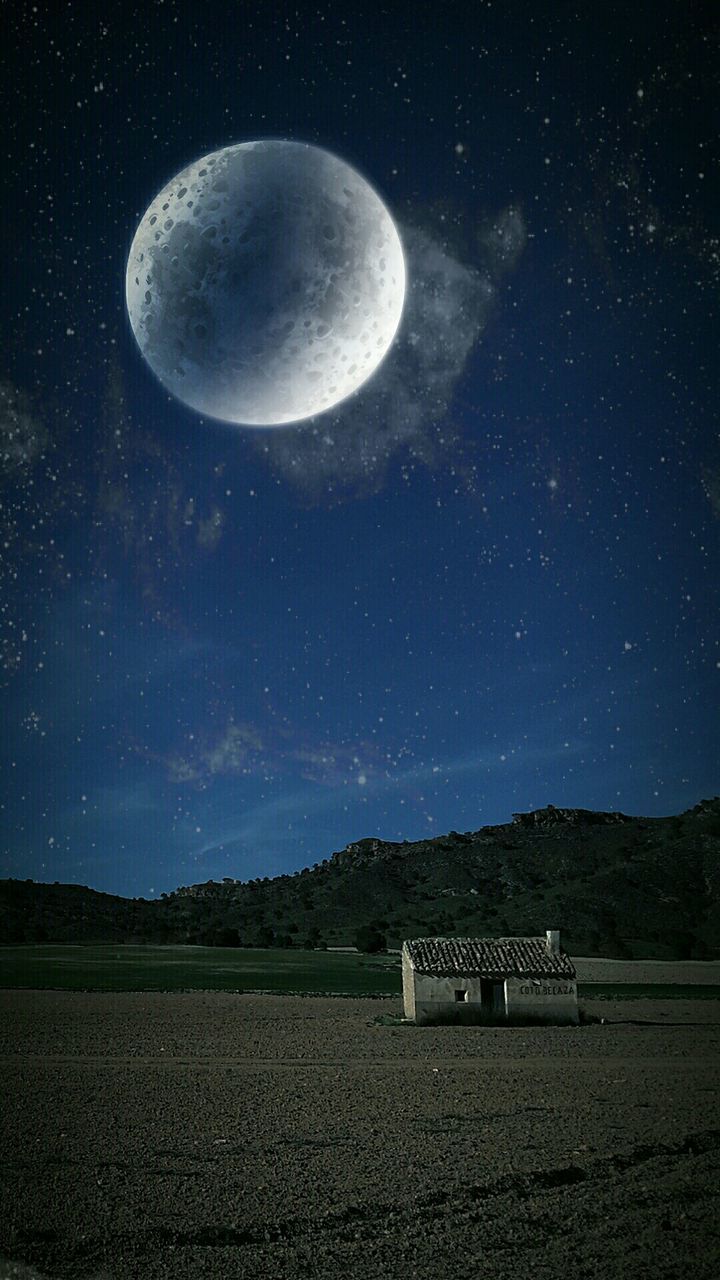 Majestic moon over house on grassy field