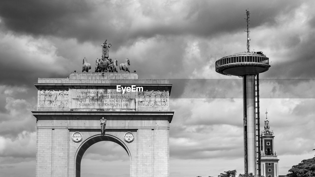 Low angle view of town arch against cloudy sky