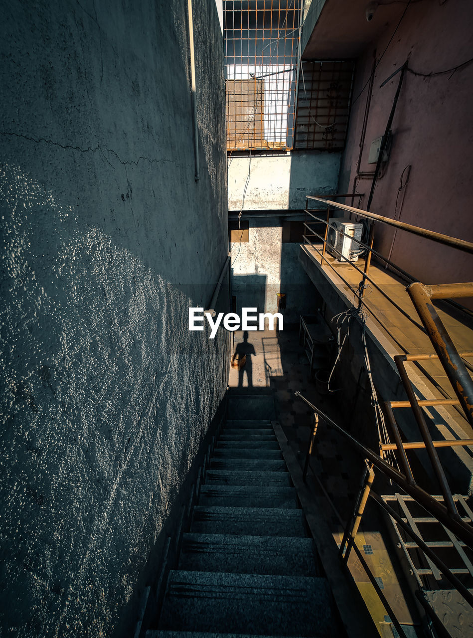 High angle view of steps amidst buildings with shadow of a man