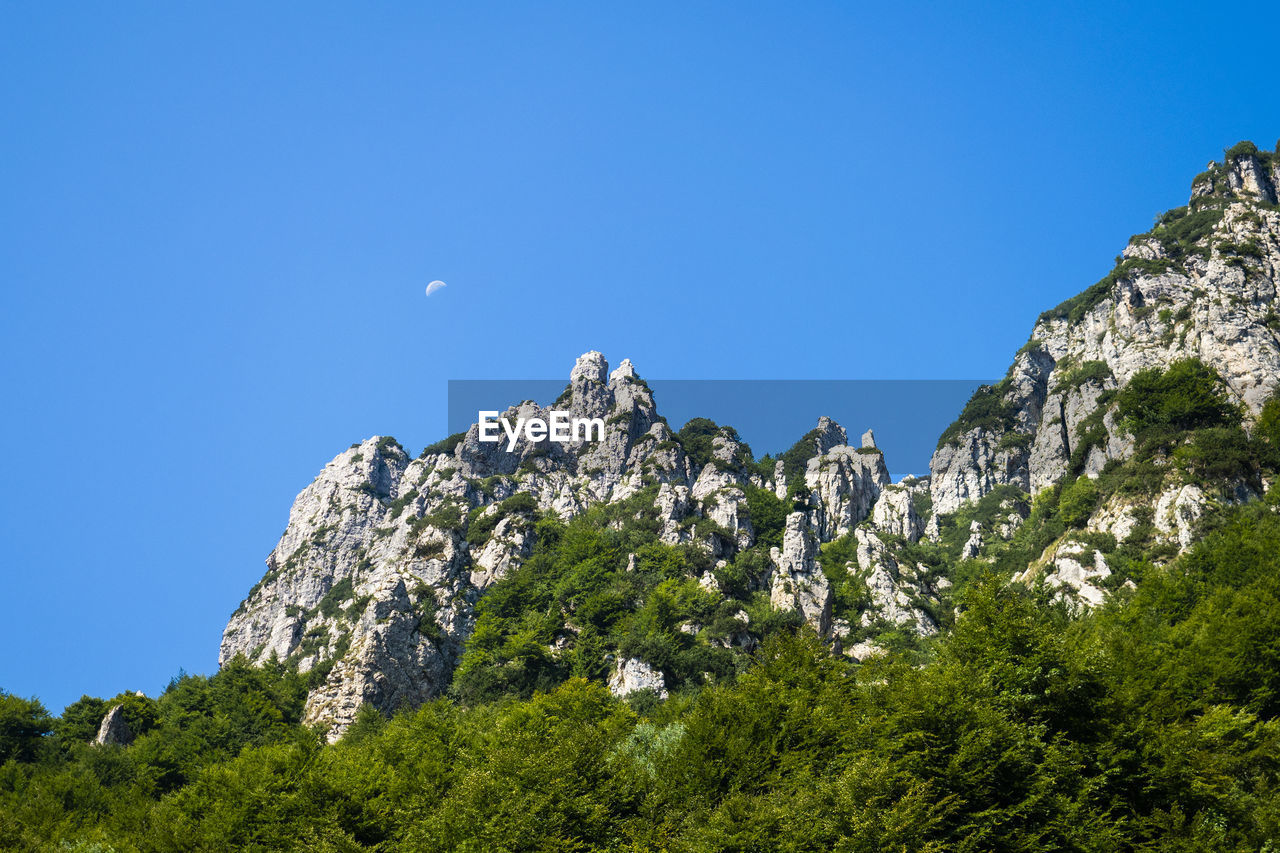 Low angle view of rocks against blue sky