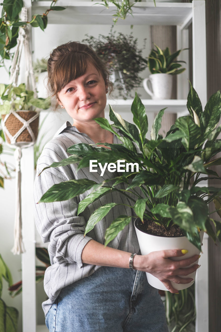 portrait of young woman standing by christmas tree at home